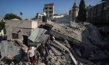 Three men stand in the remains of a building beside a Gaza church 