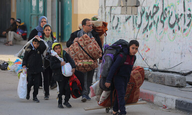 A family carry their belongings after being ordered to evacuate their home 