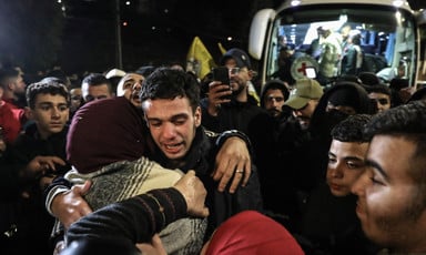 A young man hugs a women as other people look on