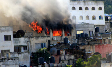 Smoke and fire can be seen from the window of a building 