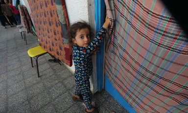 A child beside a makeshift tent at a Gaza school now serving as a shelter for displaced people 