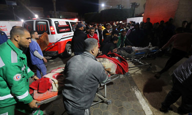 Health workers carry an injured patient on a stretcher beside an ambulance 