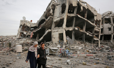 Two women walk beside a building that has been badly damaged in an Israeli airstrike 