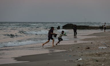 On the beach at dusk, children run from approaching waves