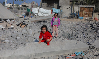 One girl kneels and one girl stands in Gaza's rubble 