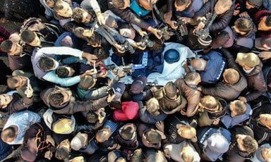 A crowd seen from above surrounds a stretcher with a press helmet