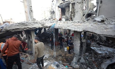 A man walks past a house destroyed in a missile attack