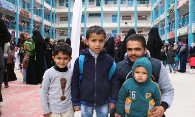 A father poses with three children in the courtyard of a school