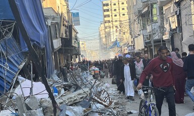 People crowd through a cityscape in ruins