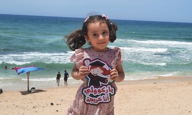 Smiling Kenzi al-Madoun, 5 years old, poses on the beach after kindergarten graduation