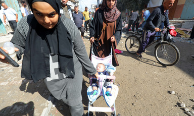 Two women push a stroller through crowded streets.
