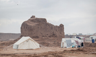 Two tents in the foreground of a desert landscape
