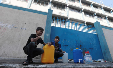 Boys kneel next to their water containers