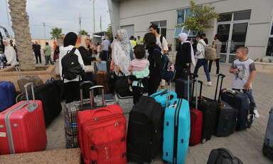 People with suitcases stand at the Rafah crossing 