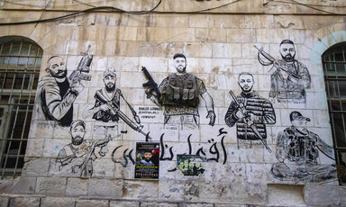 A mural depicting seven armed men is on the stone wall of a building