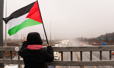 A girl waves the Palestinian flag over a highway