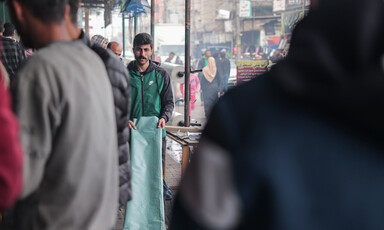 A man walks with a plastic sheet in a crowded street