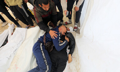 A man cries next to the body of his son