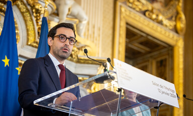 The French foreign minister Stéphane Séjourné stands at a podium in front of a European Union flag 