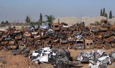 Dozens of destroyed cars and vans stacked up in an open lot