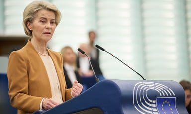 European Commission President Ursula von der Leyen stands at a podium with a microphone in front of her 
