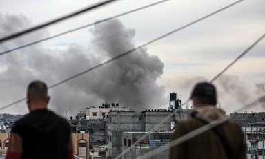 Two people look at smoke rising after an Israeli airstrike in southern Gaza 