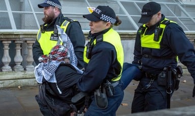 Three British police officers carry a demonstrator away