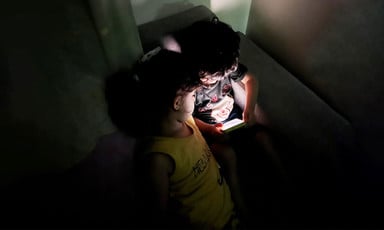 two children huddle together around a phone