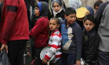 A crowd of children holding metal food containers.