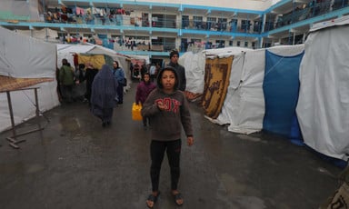 A young boy looks at the camera while standing next to tents in building courtyard