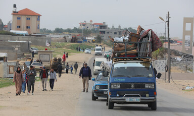 People walk beside vehicles full of belongings in Gaza 