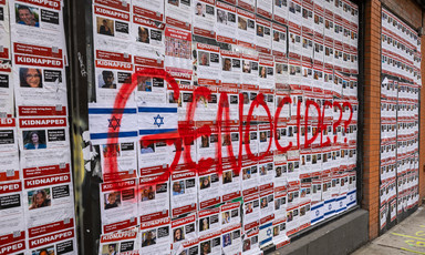 Posters bearing images of Israeli captives in Gaza with the word 'genocide' scribbled across