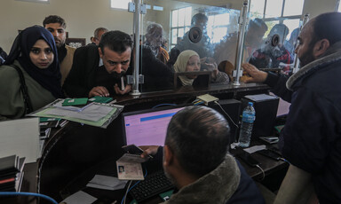 People crowd a window at a passport terminal