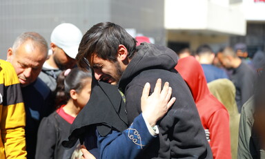 A man seen from the waist up cries as he hugs a woman