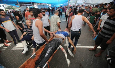 A number of men carry an injured man on a stretcher. 