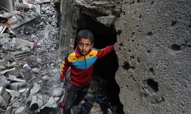 A boy wearing a track suit amid the ruins of a Gaza home destroyed by Israel 