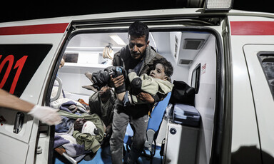 A medic carries an injured child out of an ambulance 