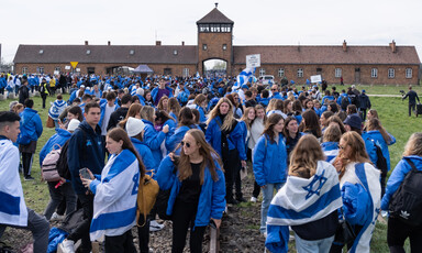 School children stand draped in Israeli flags outside Auschwitz