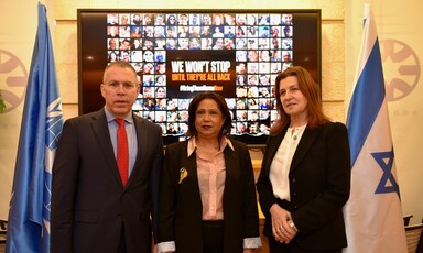 Three people stand in front of a photo collage 