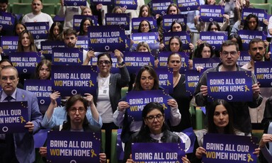 A number of people hold up placards reading Bring Our Women Home 