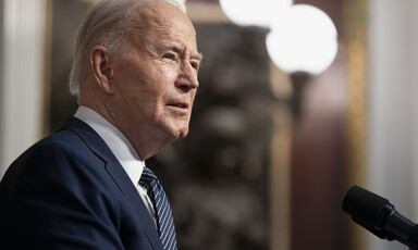 Joe Biden at a microphone with three lights above him