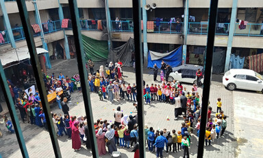 A view of a schoolyard taken from behind some metal bars 
