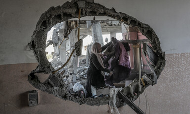 A woman can be seen through a hole in a badly damaged building 