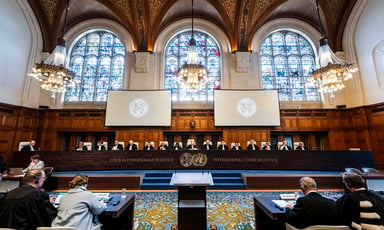 Judges sit at a long table below stained-glass windows in wood-paneled courtroom