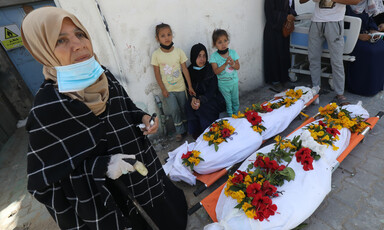 A woman and three children beside shrouded bodies in southern Gaza 