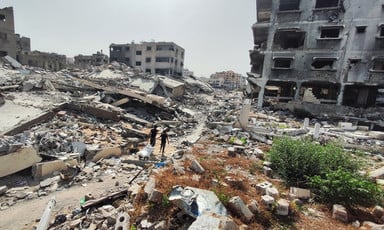 Two people walk amid rubble toward the remains of buildings which have been attacked in Gaza City 