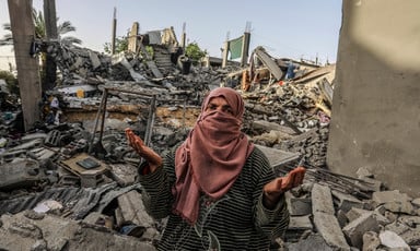 A woman stands in the middle of a home that has been destroyed in southern Gaza 