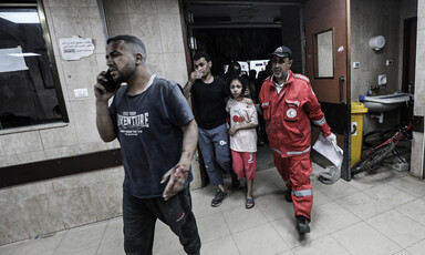A medic walks beside a girl and a man in a Gaza hospital 