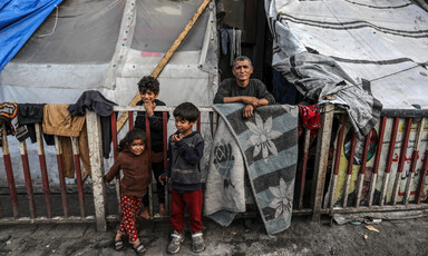 Three children and one adult stand beside a makeshift tent in southern Gaza 