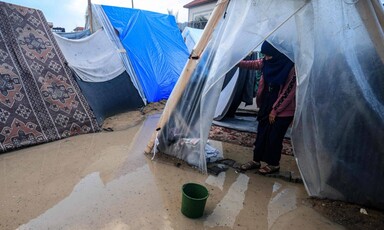 A woman stand ankle deep in brackish water in a tent